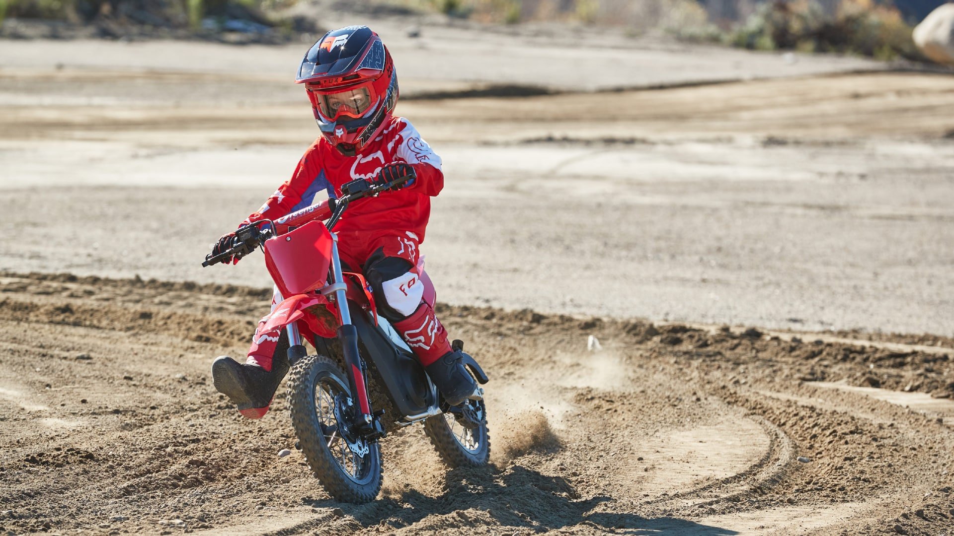 Youth on electric Honda dirt bike going through a turn.