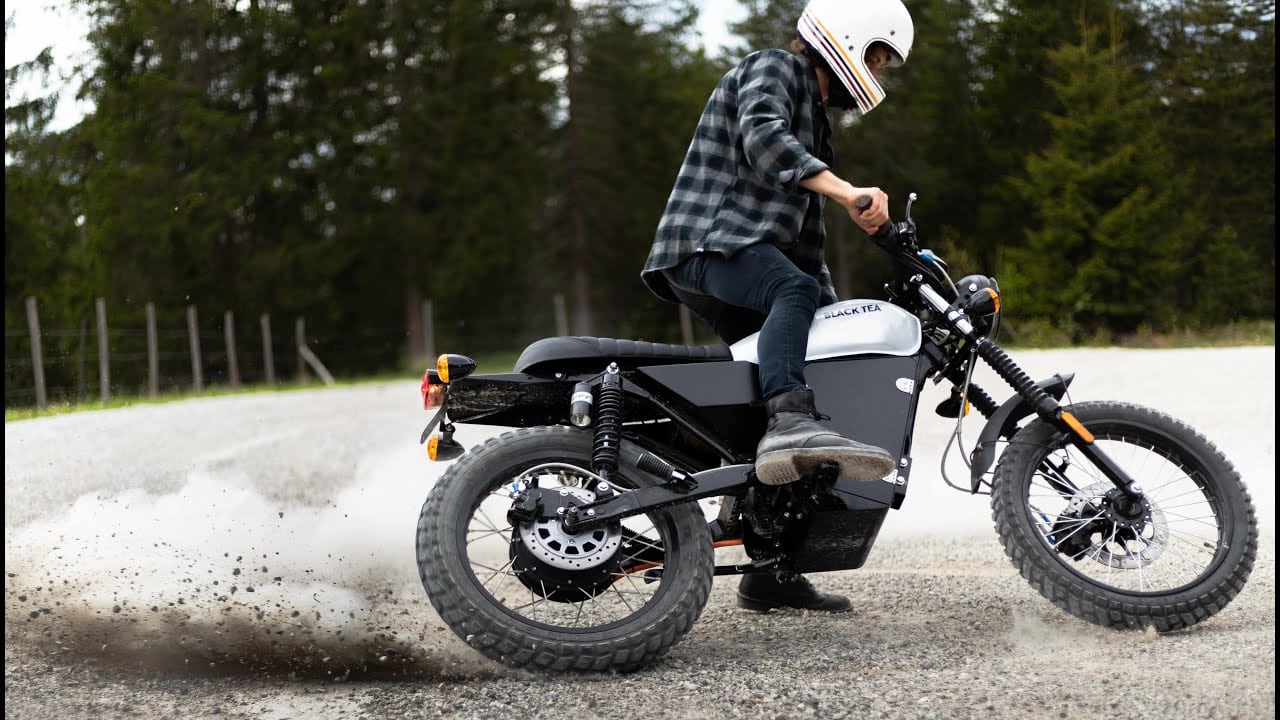 Black Tea Bonfire scrambler doing donuts in a gravel lot.